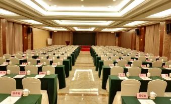 a large conference room with rows of chairs and tables , green tablecloths , and a red centerpiece at Rome Hotel