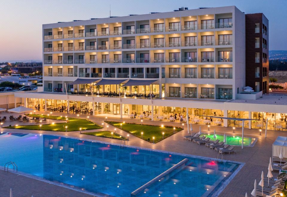 a large hotel with a swimming pool surrounded by grass and people in the pool area at Ivi Mare - Designed for Adults by Louis Hotels