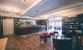 a large , open - plan restaurant with wooden floors , white walls , and multiple dining tables , as well as a bar area with stools at The Grange Hotel Brent Knoll