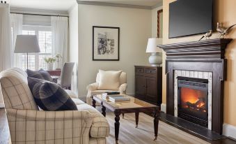 a cozy living room with a fireplace , two couches , a coffee table , and a flat - screen tv at Inn at Perry Cabin