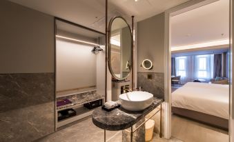a modern bathroom with a large oval mirror above a white sink and a unique wooden headboard at Hengxing Mercure Hotel