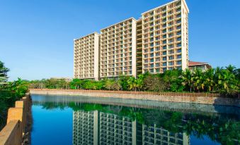 a large apartment building surrounded by trees and a body of water , creating a picturesque scene at Sanya Xizang Hotel