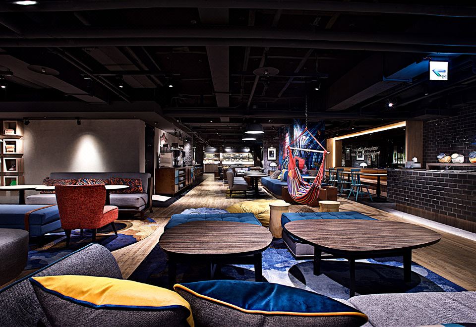 a modern lounge area with a variety of seating options , including couches , chairs , and tables at Just Sleep Ximending