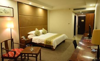 a large bed with white linens and a brown headboard is in a room with a wooden table , chairs , and a table at Spring Hotel