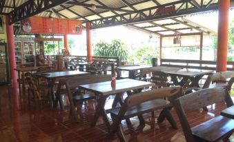 a large dining room with wooden tables and chairs , a table for several people , and a red sign hanging on the wall at Baan Ton Nam Resort SuanPhueng