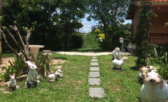 a garden with a path and statues of birds , along with a view of the ocean at Baan Ton Nam Resort SuanPhueng