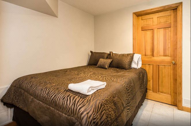 a bed with a brown zebra print blanket and two pillows is in a room next to a wooden door at Roxbury Suites