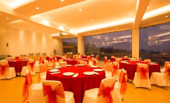 a large banquet hall with round tables covered in red tablecloths and chairs arranged for a formal event at Hotel Cianjur Cipanas