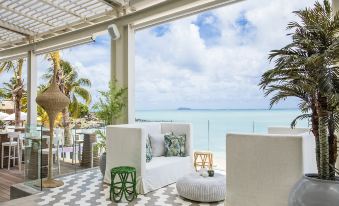 a white couch and chair on a patio overlooking the ocean , creating a relaxing atmosphere at Lux* Grand Gaube