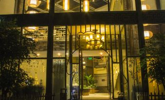 a building with a large glass window and a door , illuminated by yellow lights at night at Panda Hotel