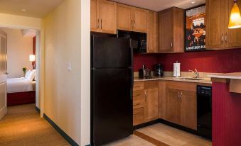 "a kitchen with wooden cabinets , a black refrigerator , and a poster on the wall that reads "" coffee ."" also a sink and a microwave" at Residence Inn Kingston