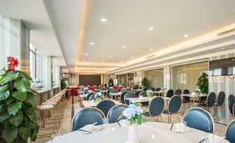 A spacious room with tables and chairs arranged in the center, suitable for business meetings or social gatherings at Hawaii International Hotel (Shenzhen International Convention and Exhibition Center)