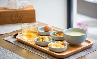a tray with a glass of tea , a bowl of cereal , and a plate of food at Floral Hotel · Mowan hotel (Tongli Ancient Town)