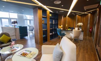 a modern living room with wooden paneling , white couches , and blue chairs arranged around coffee tables at Fraser Place Puteri Harbour, Johor