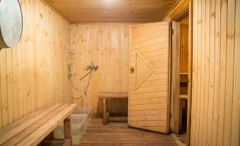 a wooden bathroom with a bench , shower , and trash can , as well as the light shining through a door at Greenberg
