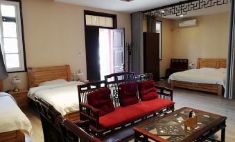 A room with two beds, a table, and chairs positioned next to each other in the center at 7 Sages International Youth Hostel