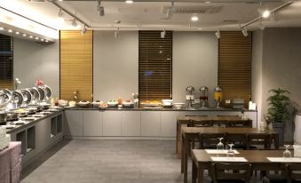 a modern kitchen with a long counter and wooden tables , featuring a variety of dishes and utensils at Am Hotel