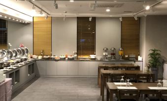 a dining area with a long counter filled with food , and several tables and chairs at Am Hotel