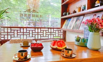On the wooden table in front of the window, there are cups and bowls at Zhouzhuang Latte Play Stone Mulan Hotel