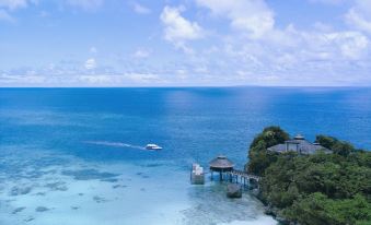 a picturesque view of the ocean , with a small boat floating in the water and a wooden pier extending into the clear blue water at Shangri-La Boracay