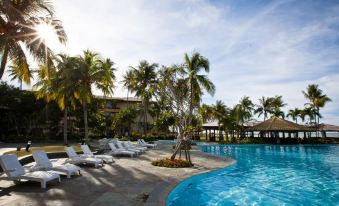 a resort with a large pool surrounded by palm trees , lounge chairs , and a bar at Palm Beach Resort & Spa