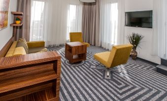 a living room with yellow chairs , a wooden coffee table , and a flat - screen tv mounted on the wall at Hotel 99