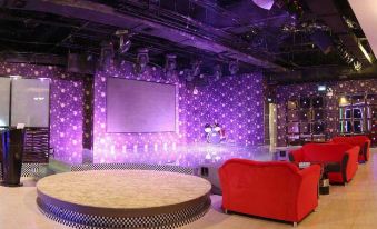 a large , circular seating area with red chairs and a purple backdrop is in a dimly lit room at Diamond Hotel