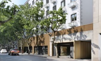 There is a building with an umbrella in front of it on the sidewalk, next to another large white building at Ginco Hotel