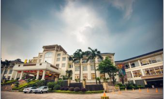 a large hotel building surrounded by trees , with cars parked in front of it on a city street at Royal Hotel