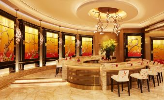 A spacious room with marble counters and chandeliers in the center, accompanied by side tables at Wynn Palace