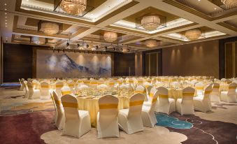 a large banquet hall with multiple tables set up for a formal event , possibly a wedding or conference at Sanya Xizang Hotel
