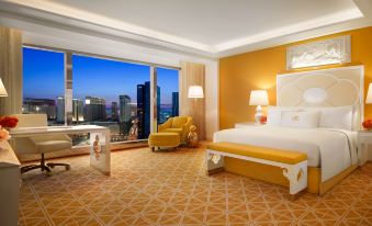 The bedroom features large windows, a carpeted floor, an armchair, and a small table next to the bed at Wynn Palace