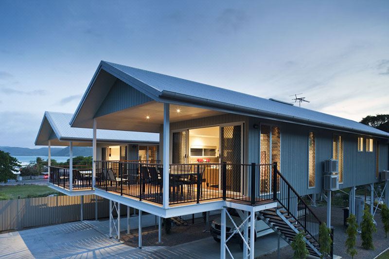 a two - story house with a balcony and a living room on the second floor , all under a gray roof at Island Villas