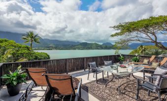 a patio overlooking a body of water , with several chairs and a dining table set up for outdoor relaxation and dining at Paradise Bay Resort