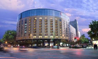 a large building with a curved roof is lit up at night , with cars and traffic in front of it at Central Hotel