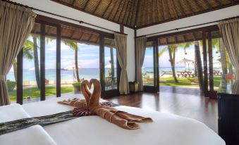 a luxurious bedroom with a view of the ocean through large windows , featuring a bed with two hearts placed on it at Mali Resort Pattaya Beach Koh Lipe