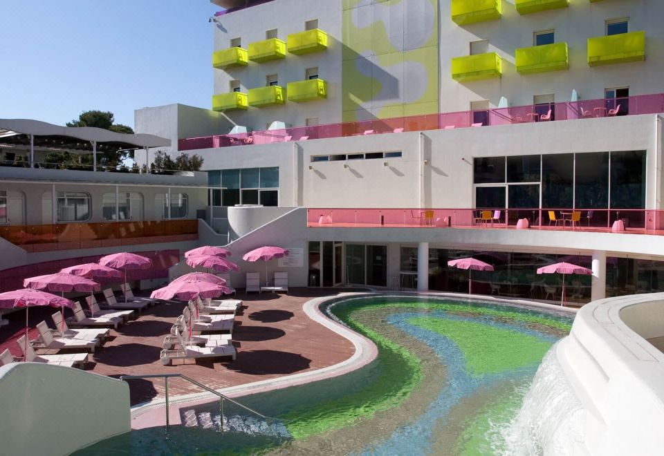 a modern hotel with a large swimming pool , umbrellas , and pink umbrellas in front of the building at Semiramis Hotel