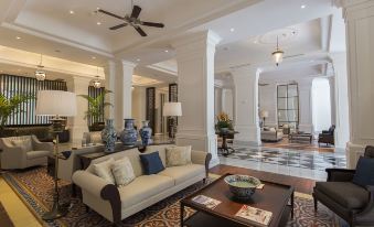 a large , elegant living room with white couches and chairs arranged around a coffee table at Plataran Heritage Borobudur Hotel