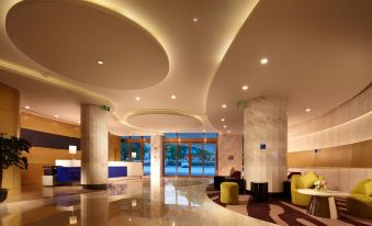 a modern hotel lobby with a curved ceiling , marble floors , and large windows that offer views of the city at Holiday Inn Express