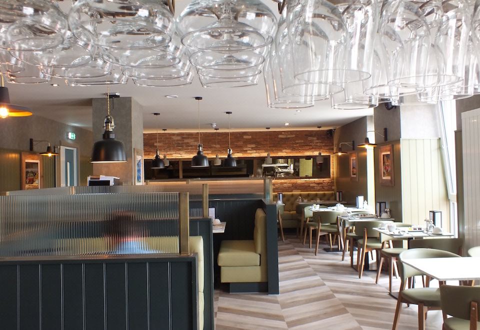 a modern restaurant with wooden tables and chairs , large windows , and hanging glass pendants over the dining area at The Garrison