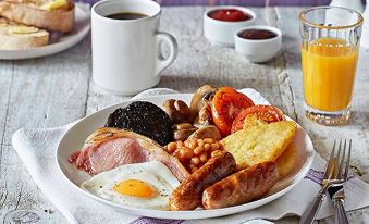 a plate of breakfast food , including a plate of ham , eggs , beans , toast , and sausage , is displayed on a table next to at Margate