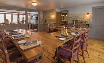 a large wooden dining table is set with plates , glasses , and napkins in a restaurant at Colby Hill Inn