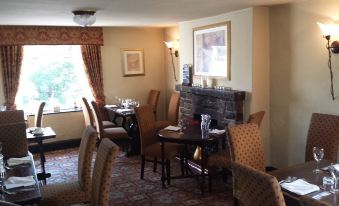 a cozy dining room with a fireplace and a group of chairs arranged around it at The Stanley Arms