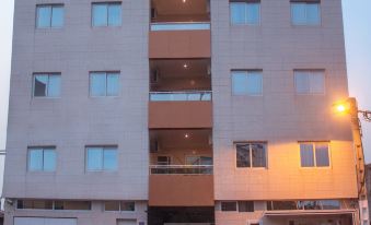 a tall white building with multiple windows and a parking lot in front of it at Residence Maryka II