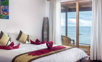 a well - decorated bedroom with a large window offering a view of the ocean , featuring a bed with white bedding and pink towels at Sali Bay Resort