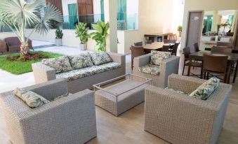 a modern living room with gray sofas and a dining table , surrounded by palm trees and a swimming pool at Star Hotel