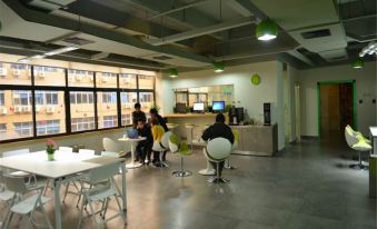 A clean office space lacking furniture, except for tables and chairs at Qiyou Capsule Youth Hostel