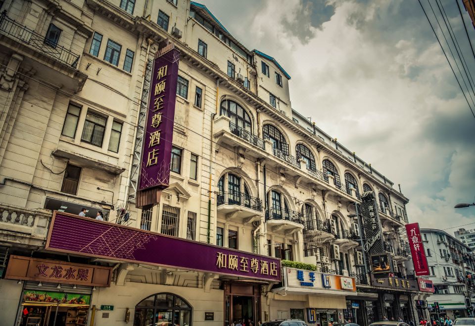 There is a large building with people on the street in front and an old clock tower above it at Yitel Premium (Shanghai people's Square Nanjing Road Pedestrian Street)