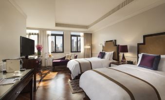 The bedroom is furnished with large windows, beds, and a desk in the middle at Metropolo Xin Cheng Hotel, The Bund Shanghai