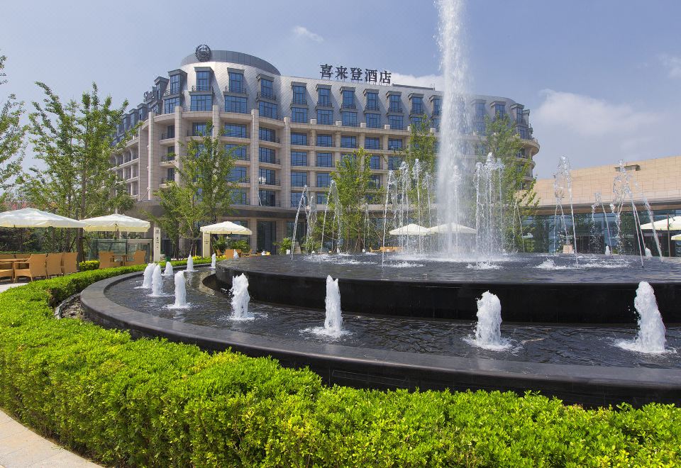 a large fountain with multiple jets shooting water into the air in front of a building at Sheraton Qinhuangdao Beidaihe  Hotel